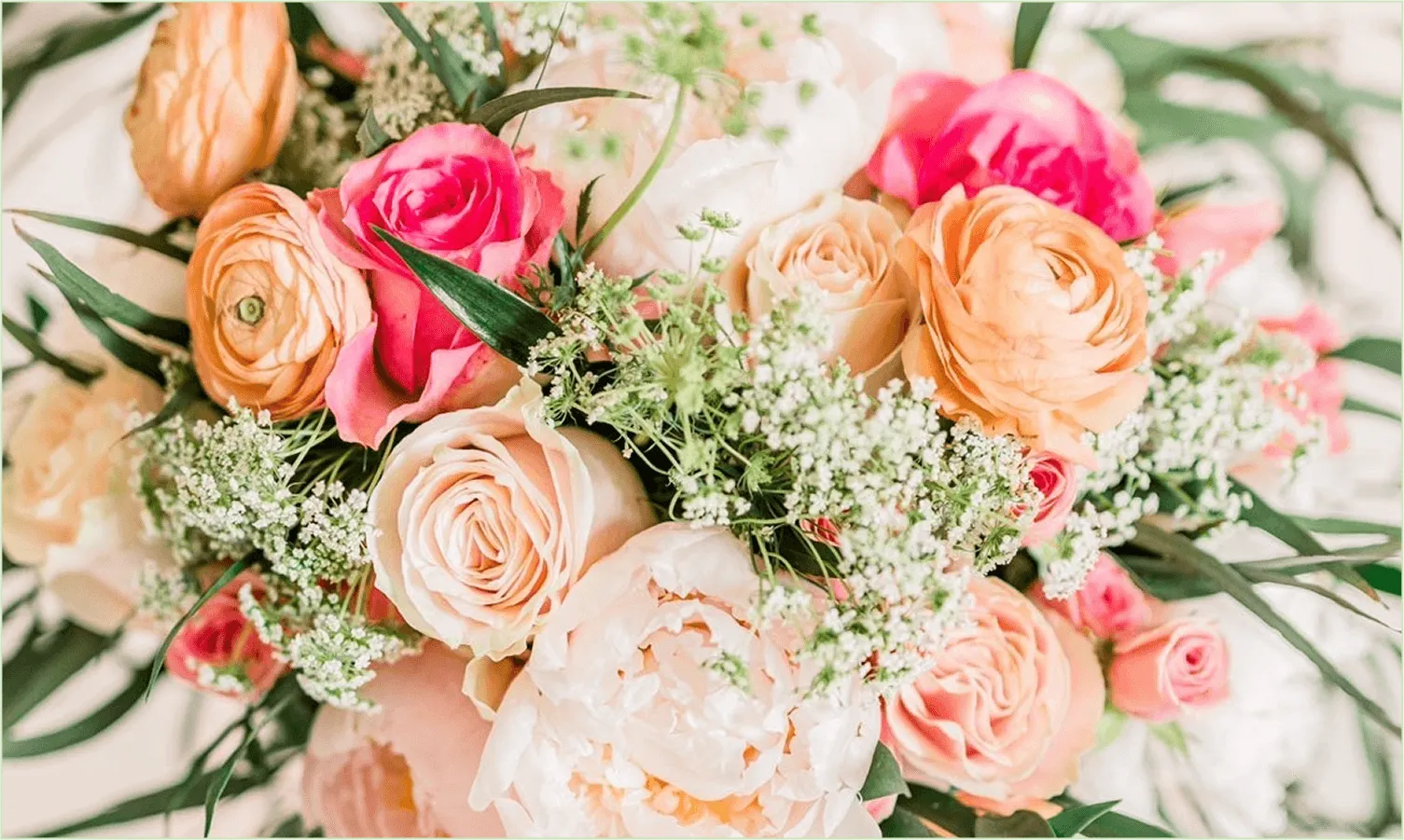 A bridal bouquet of peach ranunculus, pink roses and baby’s breath